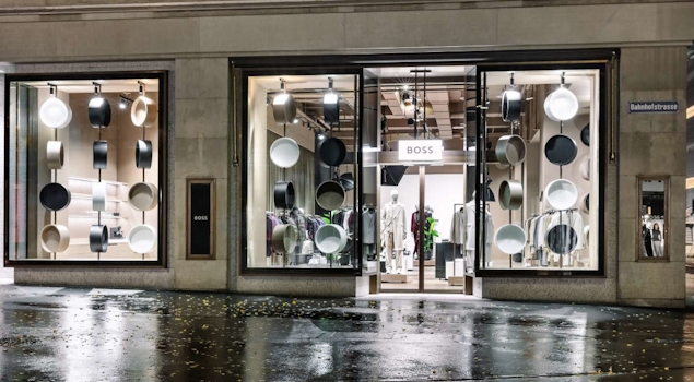 The BOSS Studio in Zurich embodies an avant-garde retail concept within a 250-square-meter space. With a nod to the brand's essence, a vibrant customisation corner and captivating window displays adorned with flashlights enchant passersby. Retail design by Studio Königshausen.